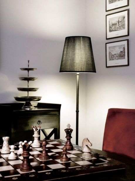 Blick in eine edel eingerichtete Zimmerecke mit Schachpiel und Schirmlampe.